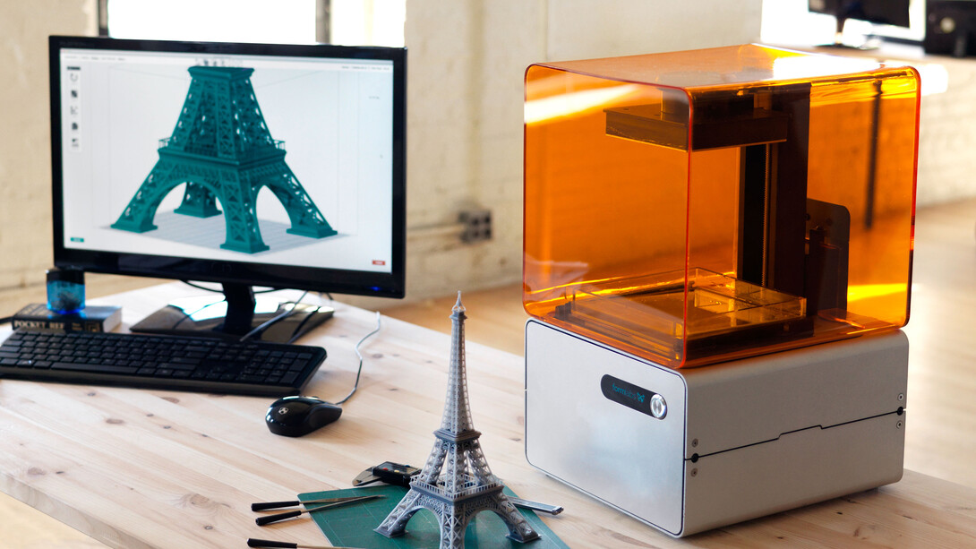 Impresora 3D junto a un modelo de la Torre Eiffel