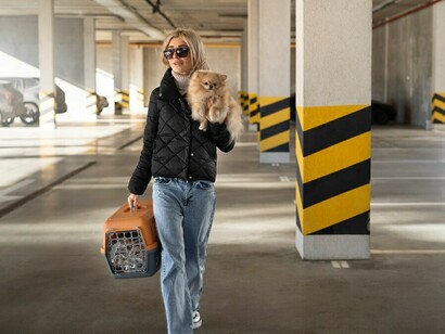 A woman at the airport holds her adorable dog while preparing to board an animal-friendly airline, ensuring a comfortable journey for her pet