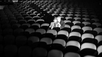 Black-and-white image of a couple seated in an empty theater