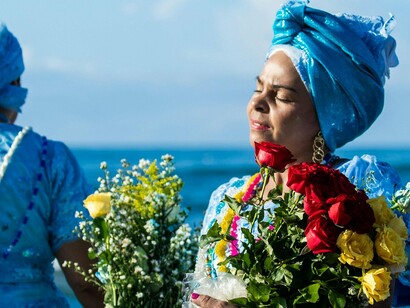 Candomblecista com oferendas.  o conceito de patrimônio imaterial que contempla complexo elementos tangíveis e intangíveis tornou-se prioridade no século XXI como respaldo de trazer aos folcloristas os estudos da devoção e dos costumes de um povo. “Os bens culturais de natureza imaterial dizem respeito àquelas práticas e domínios da vida social que se manifestam em saberes, ofícios e modos de fazer; celebrações; formas de expressão cênicas, plásticas, musicais ou lúdicas; e nos lugares" (como mercados, feiras e santuários que abrigam práticas culturais coletivas)