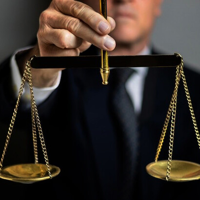 A male judge confidently posing with scales of justice in a courtroom