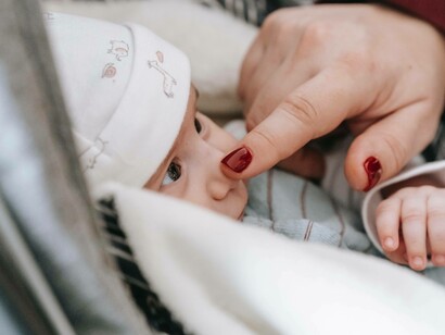 A baby having their nose poked by their caregiver 