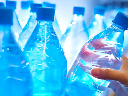Amid concerns over privatization of water resources, a person is depicted purchasing bottled water from a market shelf, highlighting the growing reliance on commercialized alternatives for hydration
