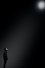 A man poised beneath a spotlight's glow, capturing a moment of dramatic intensity