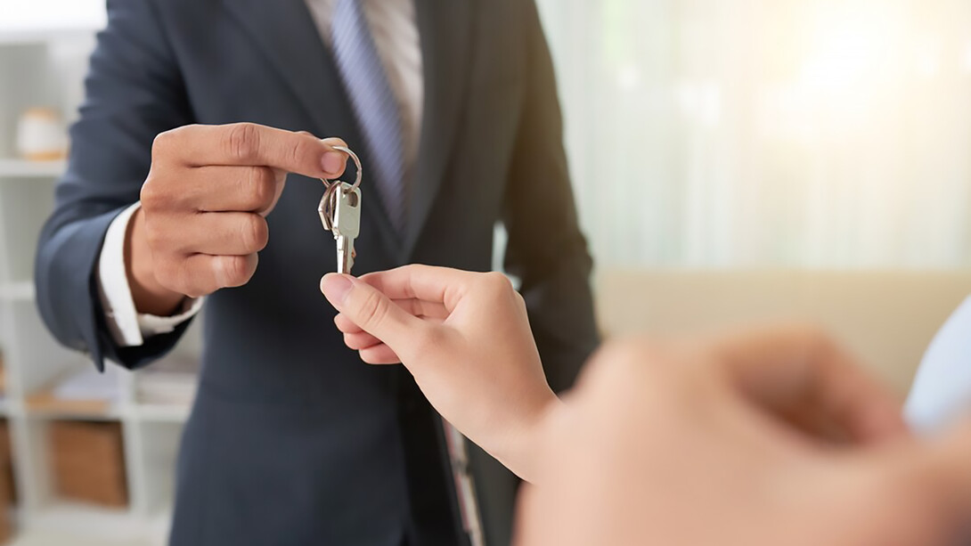A beaming couple receiving the keys to their new house from a real estate professional, capturing the joy of homeownership