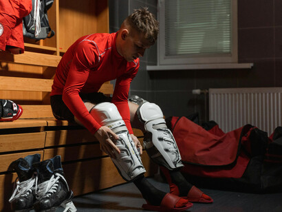 A male athlete in a red long-sleeve shirt and white knee pads, focused and prepared for competition, reflecting dedication and peak athletic performance