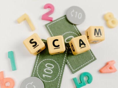 The word “scam” assembled from colorful letter tiles, reflecting how seemingly ordinary interactions can conceal cyber threats