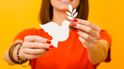 A woman gracefully cradles a paper bird and extends an olive branch, embodying symbols of peace with a poignant and hopeful gesture