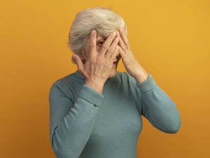 An older woman covers her face as Alzheimer’s disease progressively affects memory and cognitive function