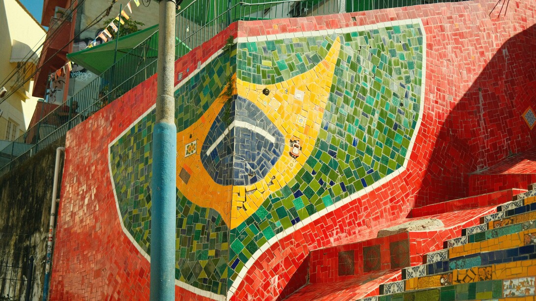 Mosaico da bandeira do Brasil decora muro de uma casa. O ponto de partida para entender os sotaques no Brasil está na chegada dos portugueses no século XVI. Inicialmente, o contato entre os colonizadores e os povos indígenas resultou em um período de bilinguismo, no qual as línguas indígenas eram amplamente faladas. O tupi, por exemplo, teve um papel essencial na comunicação entre os europeus e os nativos. Com o tempo, no entanto, o português tornou-se dominante, mas não sem absorver influências fonéticas e lexicais dos idiomas indígenas