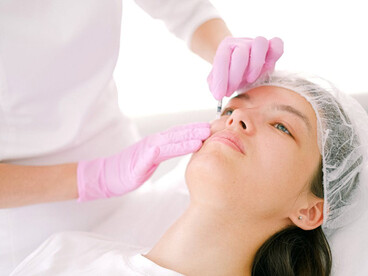 A woman undergoing a Botox treatment administered by a doctor at a cosmetic clinic