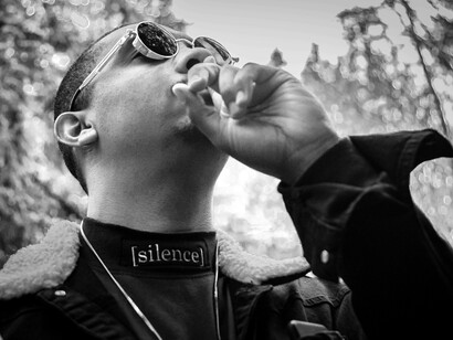 A man with his head raised and a finger to his lips is demanding silence