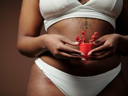 A close-up of a woman holding a red menstrual cup with both hands, symbolising openness, care, and the destigmatisation of periods
