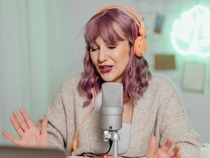A woman recording a podcast, representing the new face of the digital public square, where online communities and modern town halls take shape