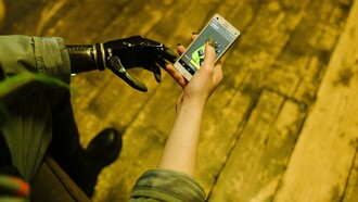 A person with a bionic arm holds a smartphone, illustrating the everyday integration of assistive technology