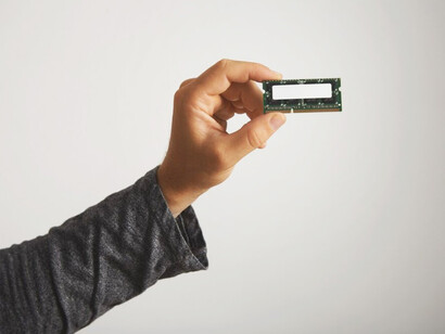 Man presenting an unmarked memory chip in a close-up shot on a white backdrop