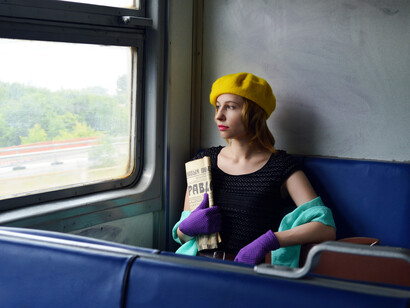 Atriz no trem segurando um jornal com notícias oficiais. Com a chegada de Stalin, o ditador queria veicular apenas obras que propagassem a mensagem oficial do governo