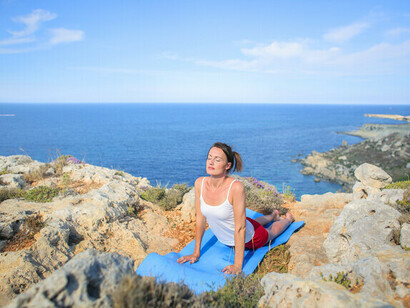 Una mujer haciendo yoga y meditación en una colina junto al mar