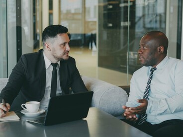 Two professionals engaged in a focused workplace discussion, representing the importance of employers addressing the financial needs of their workforce