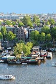 Vista de Amsterdã, Holanda. Ela ligou o motor. O barco, lento como o meu olhar, atravessava pequenas ondinhas formadas pelo vento e pelo balançar do barquinho