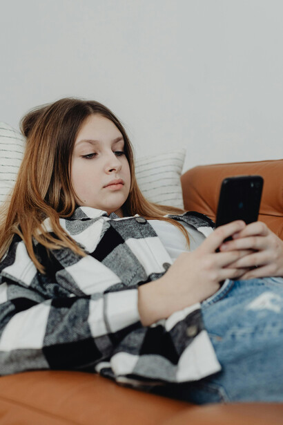 On the couch, a girl scrolls her smartphone endlessly, caught in the digital loop