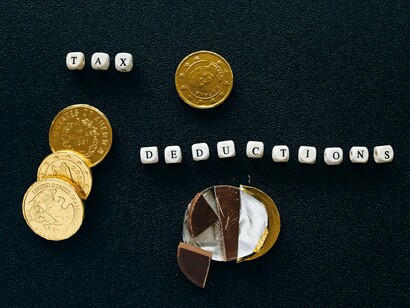Gold coins scattered around “tax deductions,” symbolising how tariffs and duties move through everyday economies