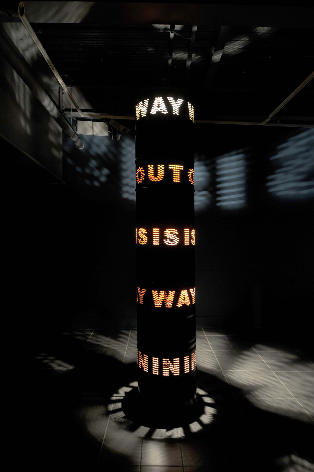 Liliane Lijn, Way Out Is Way In, 2009, Painted steel solvent drums, 3 phase motor, inverter & programmed speed & direction control chip, halogen lighting, 300 x 60cm, Image courtesy the artist