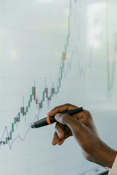 A close-up of a hand pointing at a financial graph on a digital screen, symbolizing stock market analysis
