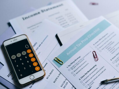 A spread of tax forms and calculators, representing the burden of financial accountability on citizens