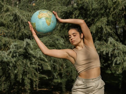 A composição une o corpo humano, a floresta e a representação do planeta em um único gesto simbólico. O texto resgata Gaia como expressão da consciência planetária e do pertencimento de todos os seres à mesma Terra
