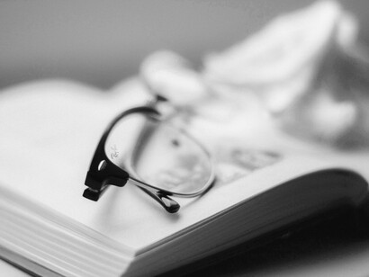 Gafas sobre un libro de filosofía abierto. La interacción dinámica entre conocimiento humano y realidad material