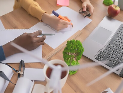 A close-up shot captures a man diligently writing in a notebook, focusing on sustainability and eco-friendly practices