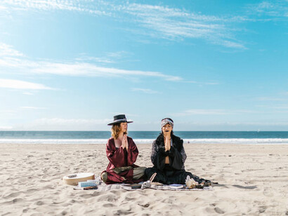 Two women harmonize with the energy of the universe, their movements on the beach reflecting a deep connection to the laws governing existence