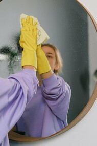 Une femme nettoyant un miroir soigneusement et se concentrant sur la tâche