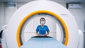 A female doctor confidently poses beside an MRI machine, showcasing the advanced technology used in modern medical imaging for accurate diagnoses