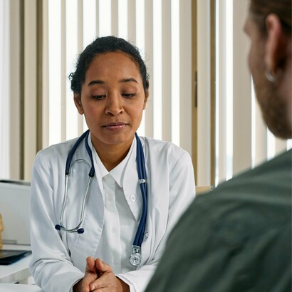 As a doctor carefully reviews health data with a patient, the image echoes the call for a healthcare system grounded in equity, not wealth