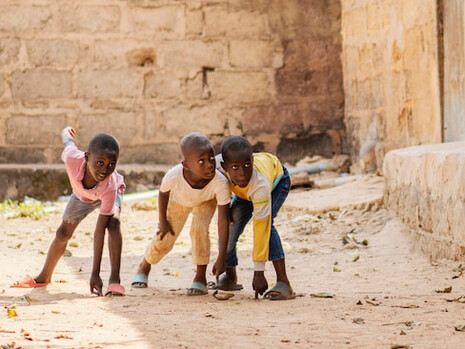 A group of children runs through the dusty streets of their village, a reminder of how infrastructure gaps affect not just education, but the daily lives of many in rural Africa