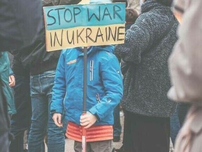 Ein Kind trägt ein Schild mit der Aufschrift „Stoppt den Krieg in der Ukraine“