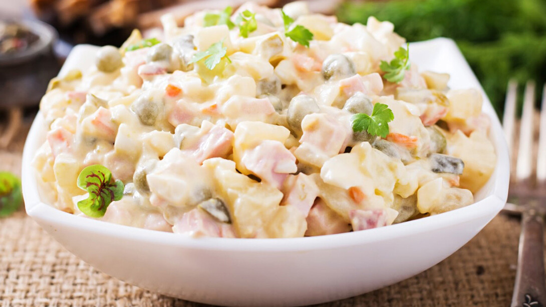 Ensalada de gallina adornada con algunas hojas de cilantro y una hoja de vinagre o acedera