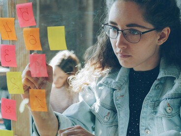 A young woman placing notes on a planning board, symbolising the role of young voices in developing solutions for a changing climate
