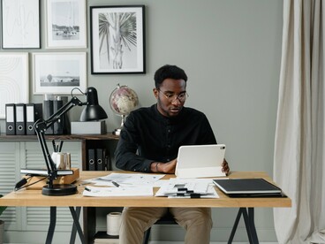 Profissional trabalha diante de um tablet, analisando informações digitais no ambiente de escritório. A recolha e interpretação de dados constituem a base para a aplicação de modelos quantitativos na gestão de custos