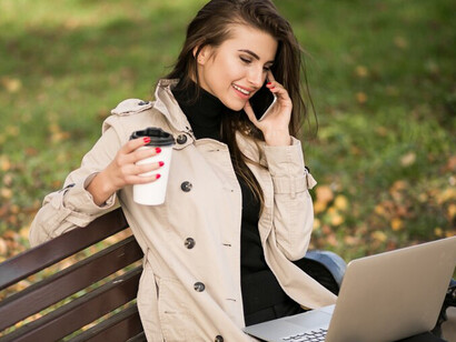 A businesswoman working on her laptop in a park during autumn, strategizing career planning as she embraces the transition of September