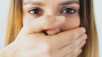 Pessoa cobrindo a boca de uma mulher