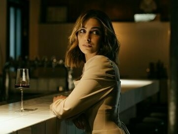 Mulher com taça de vinho. No fim das contas, talvez a vida seja como um vinho barato: começa travando a boca, mas, com o tempo, você aprende a rir das caretas e brindar a bravura que é continuar tentando