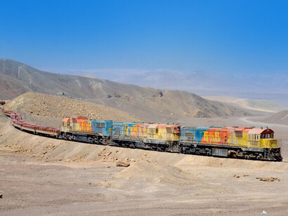 Motores FCAB Clyde escalan el acceso oriental al paso Cumbre en su camino desde una mina de cobre hacia Antofagasta y Mejillones. El tren consta de vagones plataforma cargados con placas de cobre, Chile