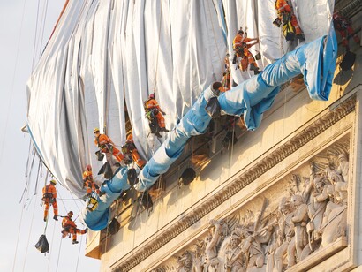 Fabric panels are being unfurled in front of the outer walls of the Arc de Triomphe—2, Photo: Wolfgang Volz © 2021 Christo and Jeanne-Claude Foundation