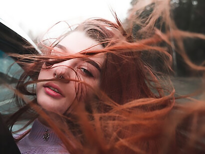 A red-haired woman leaning out of a car window