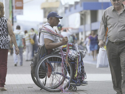 Empleo informal en Costa Rica: un hombre discapacitado vende diversos productos en una calle