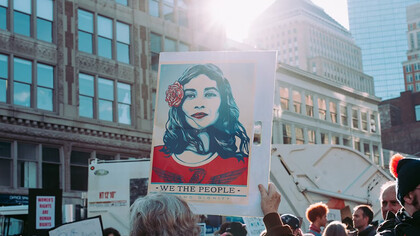 A person holding a 'We the People' sign, surrounded by a crowd—this iconic sign became a symbol of the Women's Marches held around the world