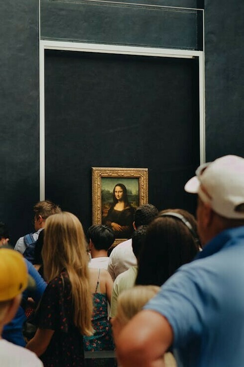 At the Louvre in Paris, people stand in awe, observing the iconic Mona Lisa, France